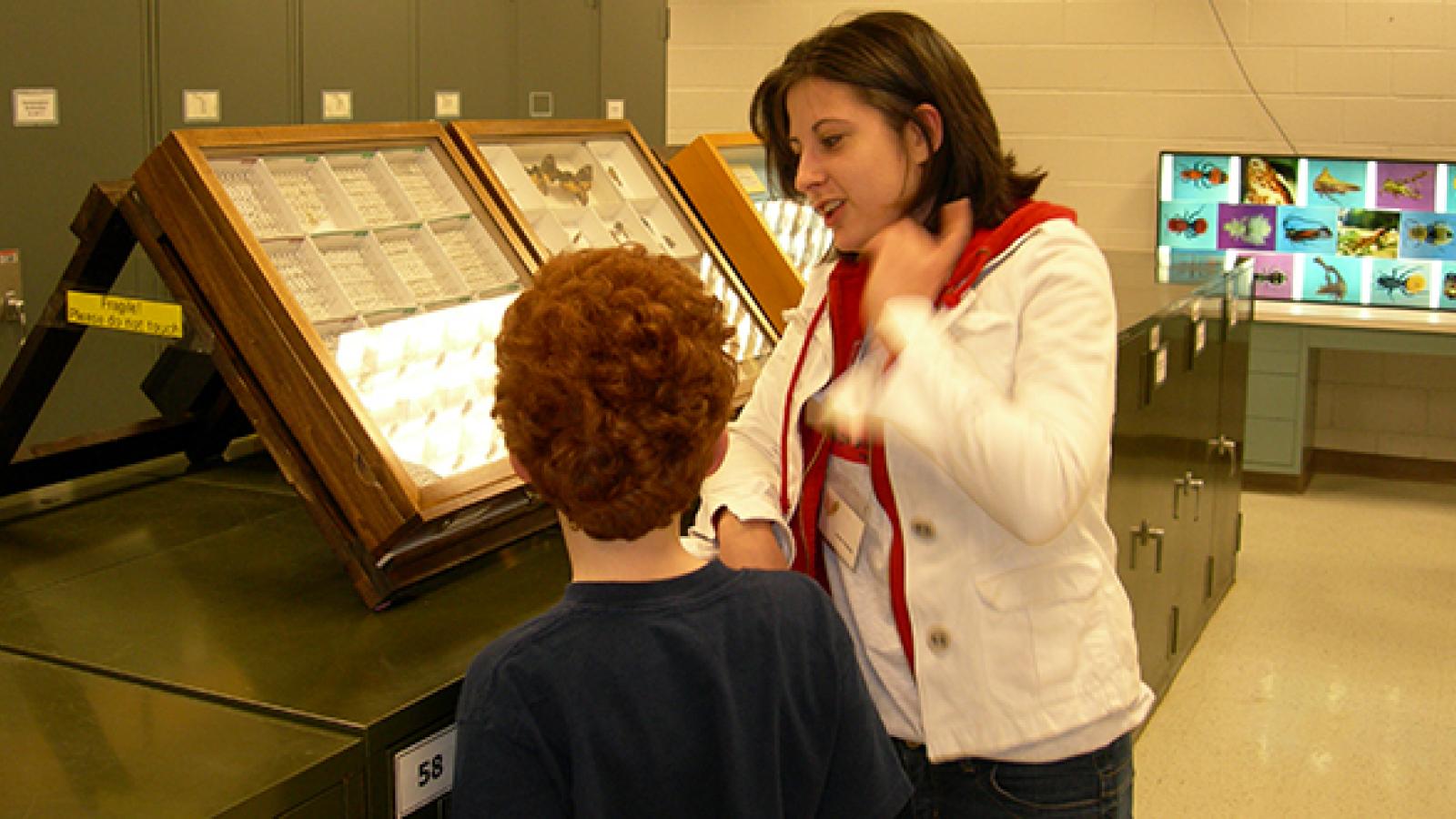 Volunteer Anne Nichols in the Triplehorn collection with a young visitor