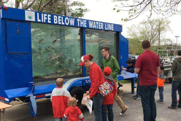 People gathered around a trailer-sized fish tank