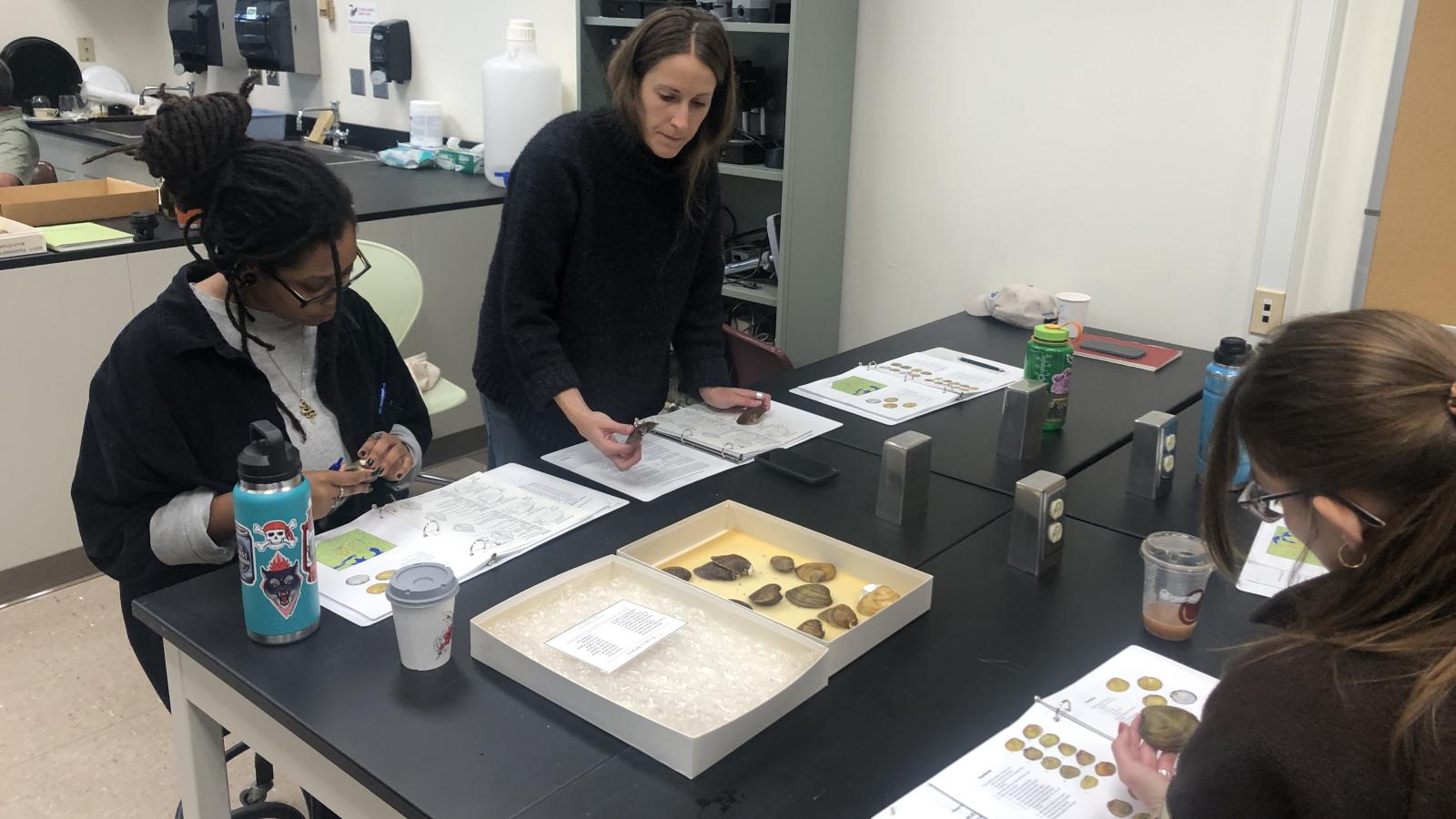 A group of workshop participants at a lab table examining freshwater mussel specimens