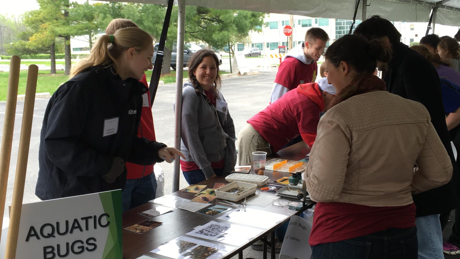 Guest and volunteers gathered around a table of aquatic bugs